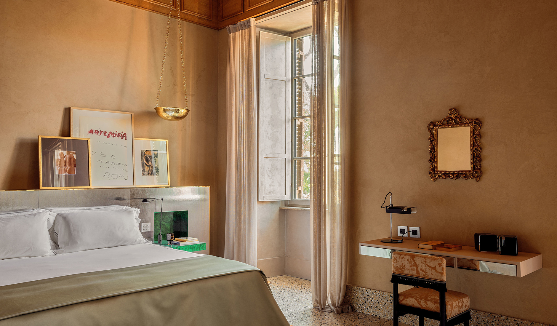Bedroom in a Ludovisi Junior Suite with gold pendant lights and framed artwork