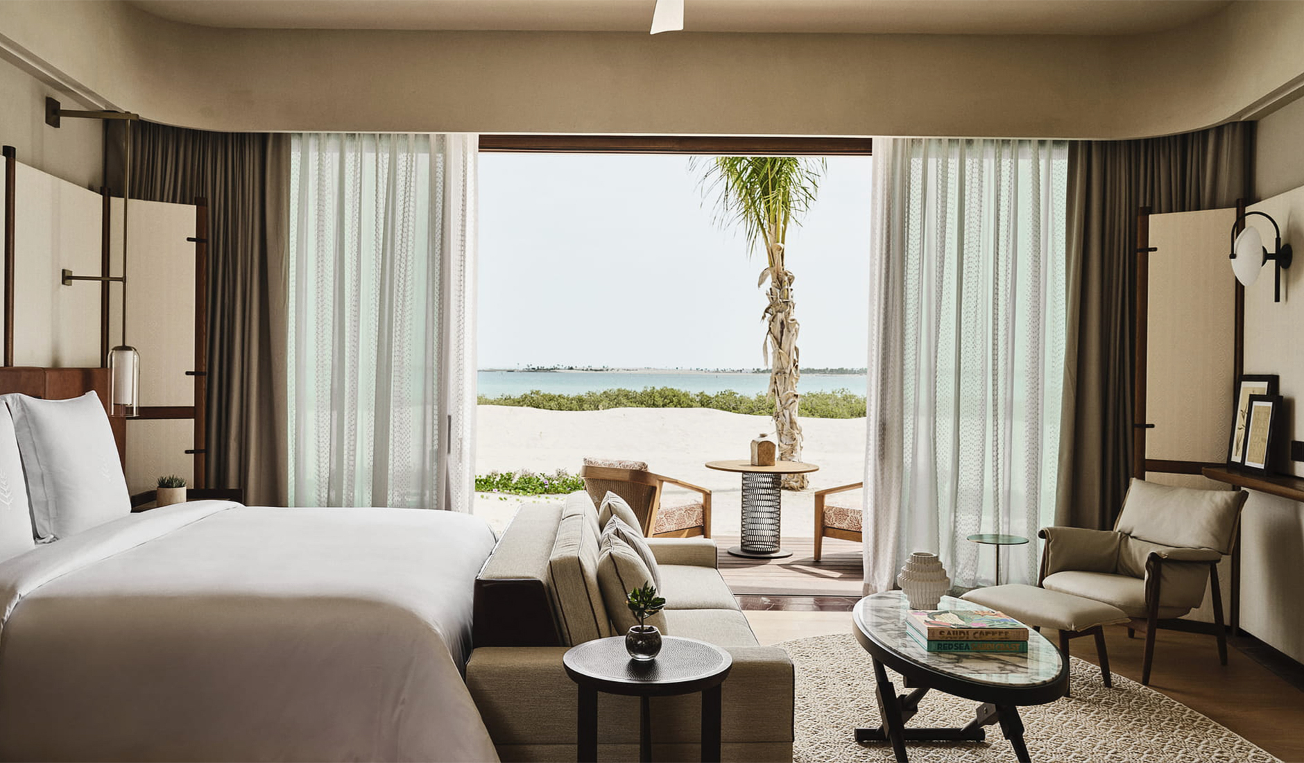 Sophisticated bedroom interior of a luxury suite at Four Seasons Resort and Residences Red Sea at Shura Island, showcasing modern Arabian chic decor and floor-to-ceiling sea views.