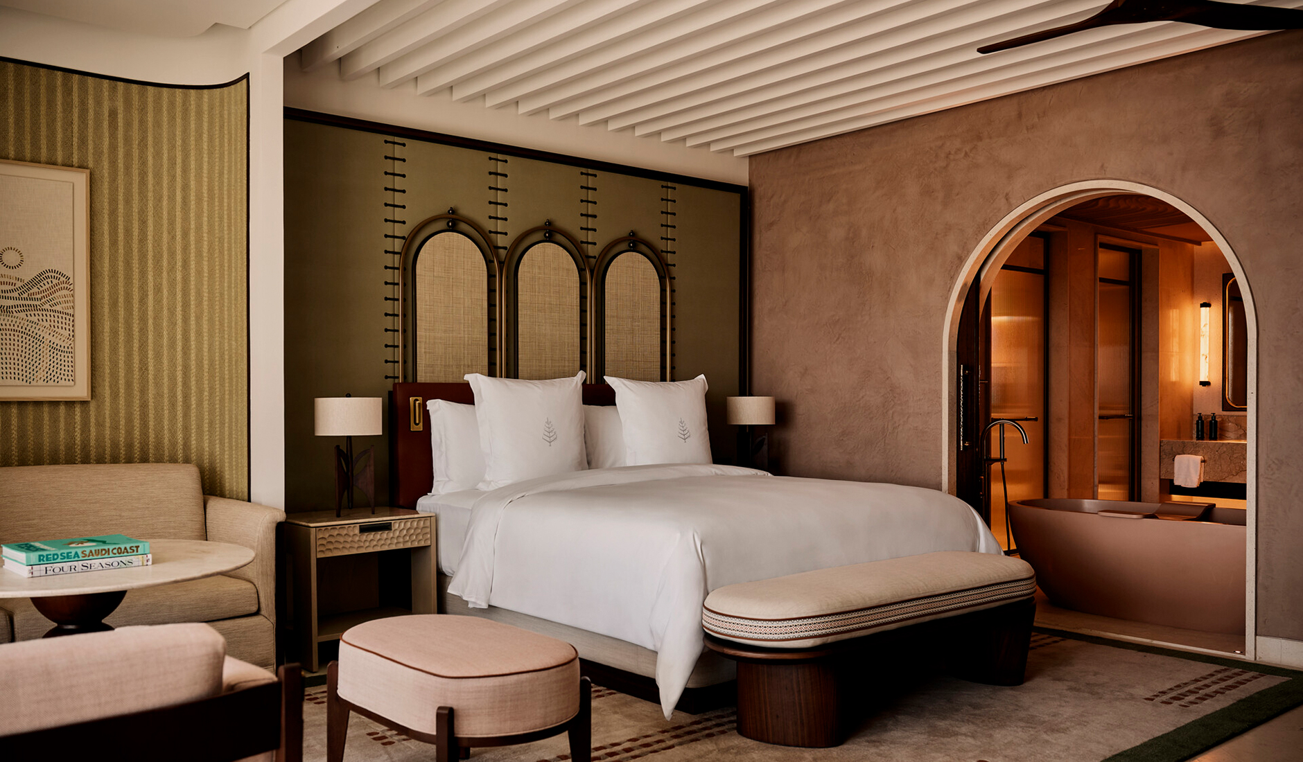 Sophisticated master bedroom at Four Seasons Resort AMAALA at Triple Bay, showcasing an elegant open-concept design with a partial view into the luxury marble ensuite bathroom.
