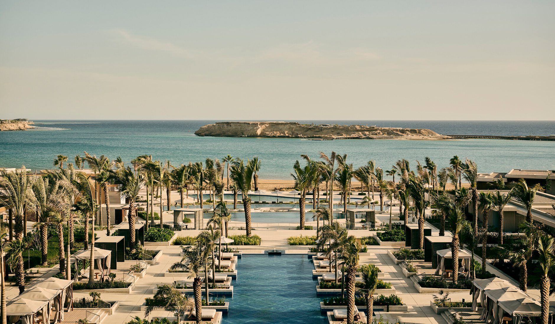 Stunning outdoor swimming pool area at Four Seasons Resort AMAALA at Triple Bay, surrounded by premium sun loungers, cabanas, and pristine coastal nature.