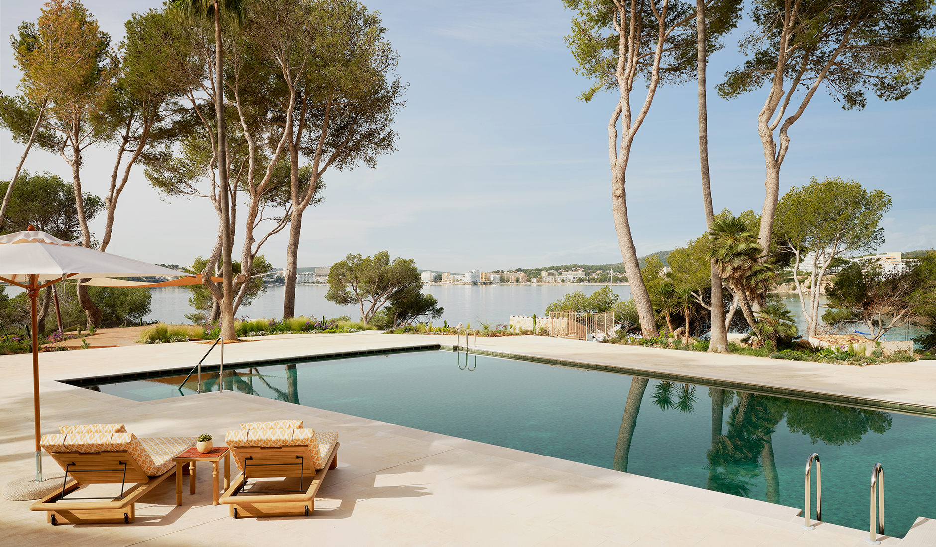 Serene outdoor infinity swimming pool and wellness area at the five-star Mandarin Oriental Punta Negra resort, framed by Mediterranean pine trees.