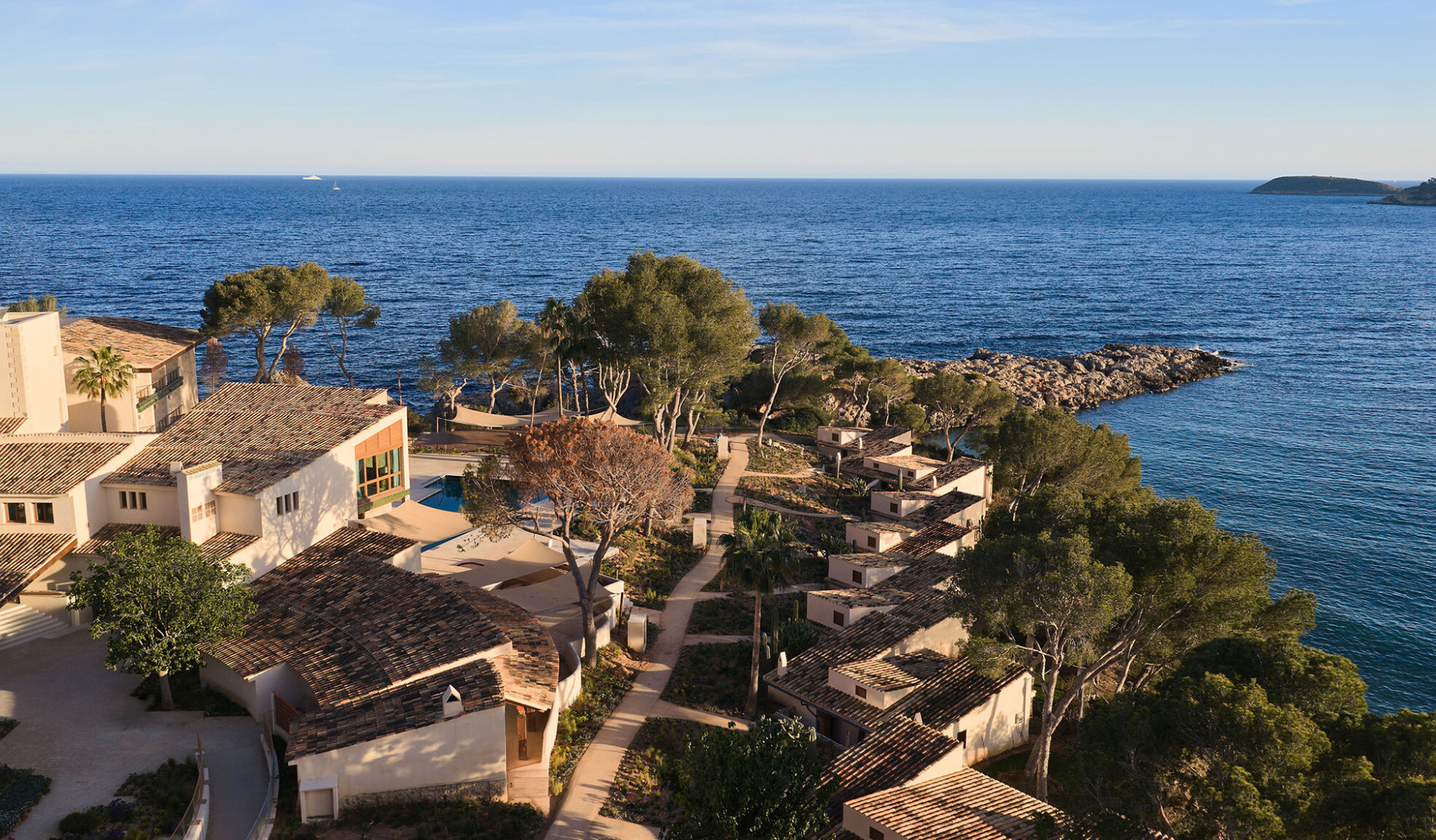 Breathtaking aerial view of the Mandarin Oriental Punta Negra resort in Mallorca, nestled on a pine-covered peninsula surrounded by the Mediterranean Sea.