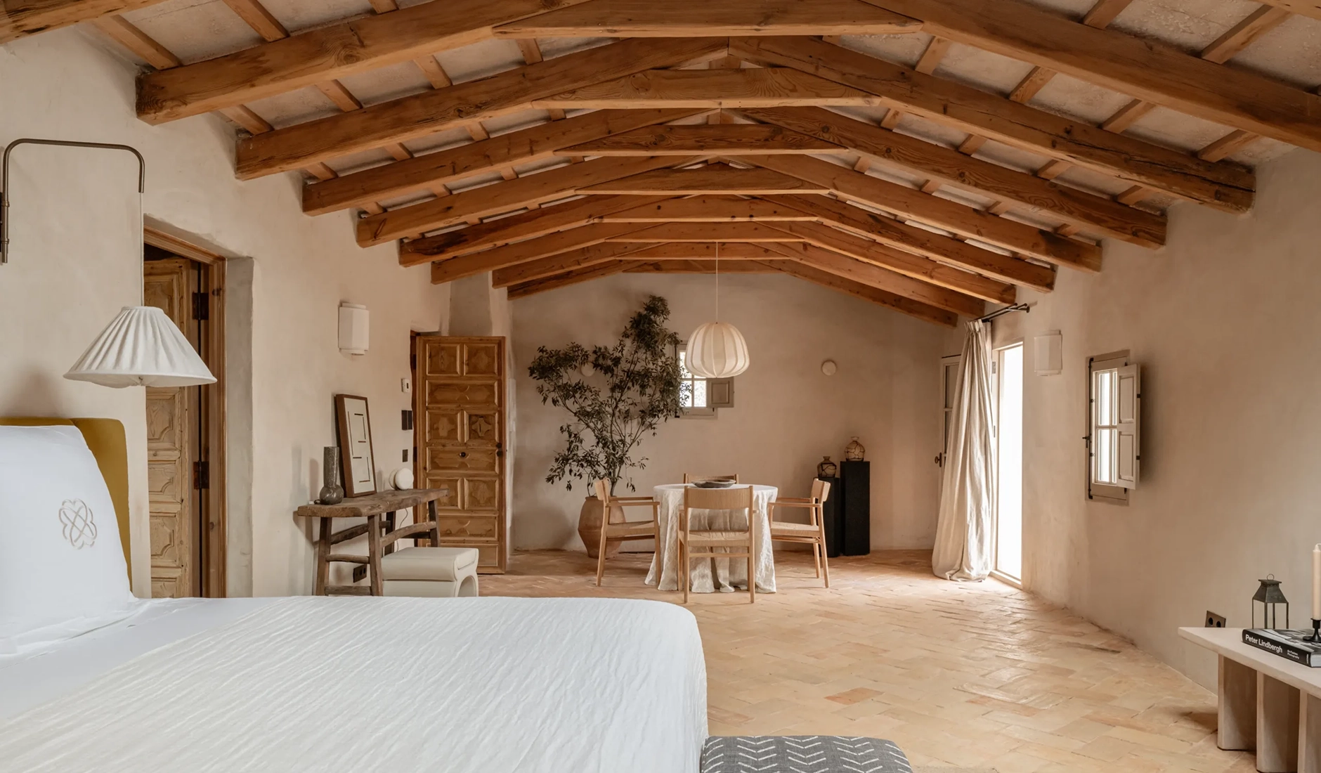 legant master suite bedroom at Vestige Binidufà Menorca, featured as one of the best hotel rooms for its minimalist design, natural textures, and rustic wooden beams.